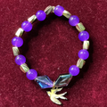 Bracelet with purple beads and a bird charm 


