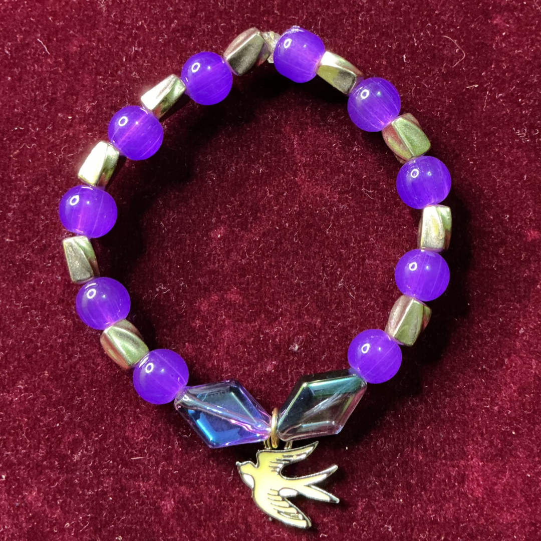 Bracelet with purple beads and a bird charm 


