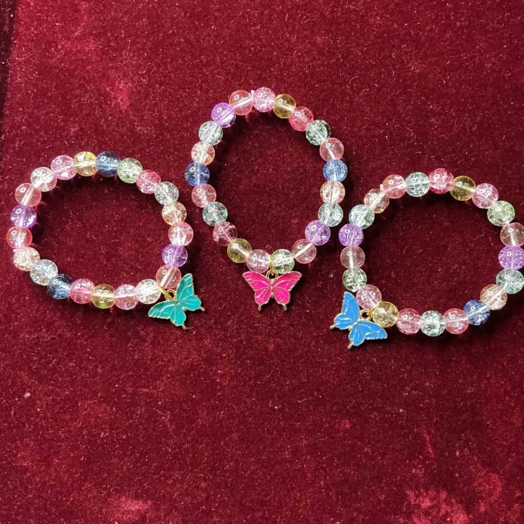 Three colorful beaded bracelets with butterfly charms on a red background