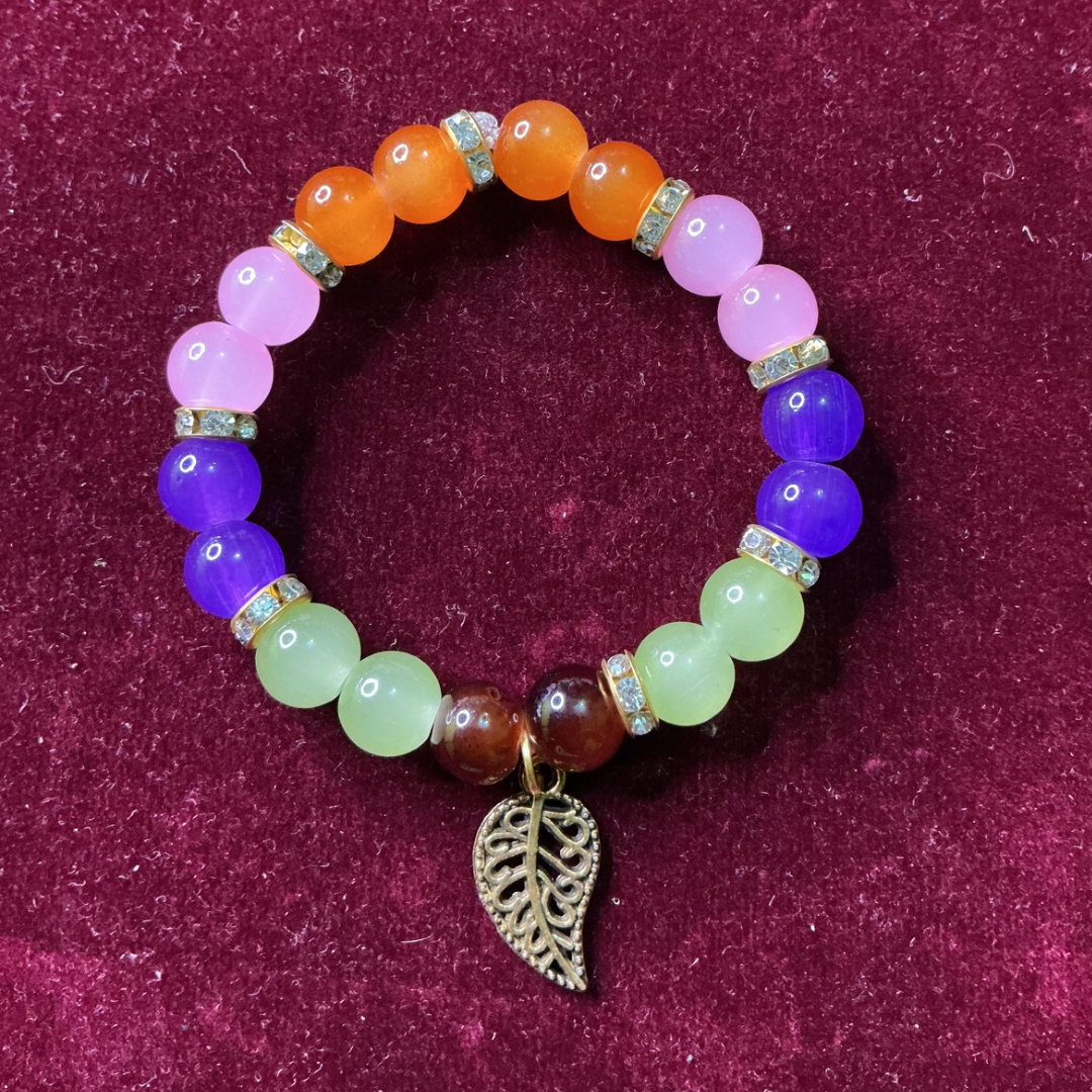 Multicolored beaded bracelet with a leaf charm on a purple background