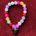 Colorful beaded bracelet with a butterfly charm on a red background