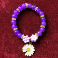 Purple beaded bracelet with a flower charm on a red background