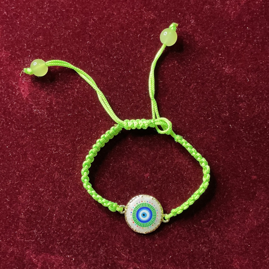 Green bracelet with a decorative evil eye charm on a maroon background