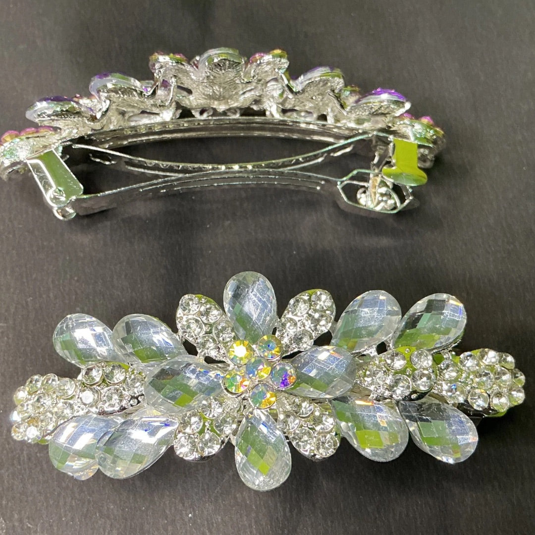 Two decorative hair clips with crystal-like stones on a dark background