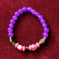 Beaded bracelet with purple and pink beads on a red background