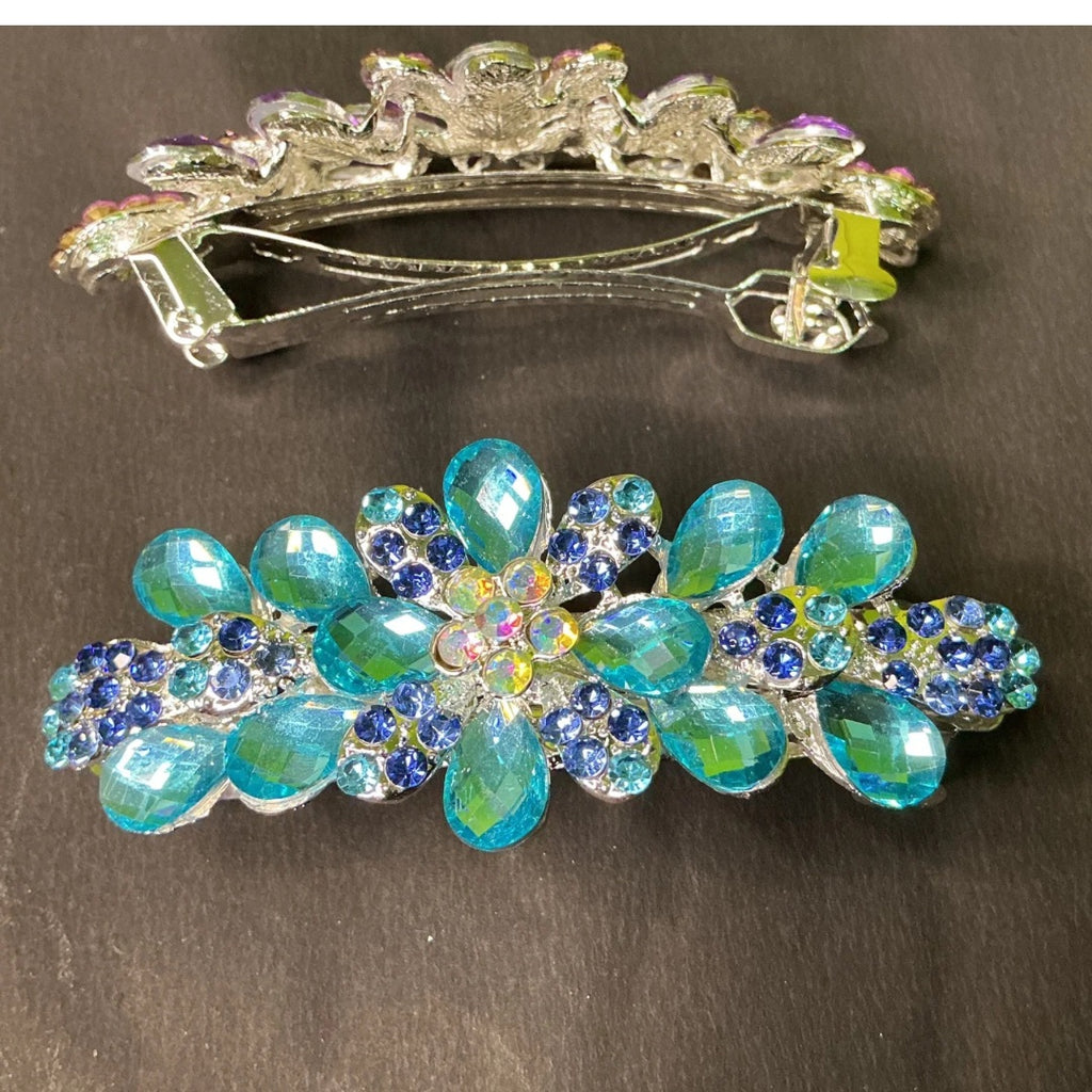 Decorative hair clip with blue and green gemstones on a dark background