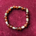 Beaded bracelet with brown and silver beads on a maroon background