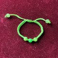 Green beaded bracelet on a maroon background