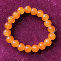 Orange beaded bracelet on a purple textured background