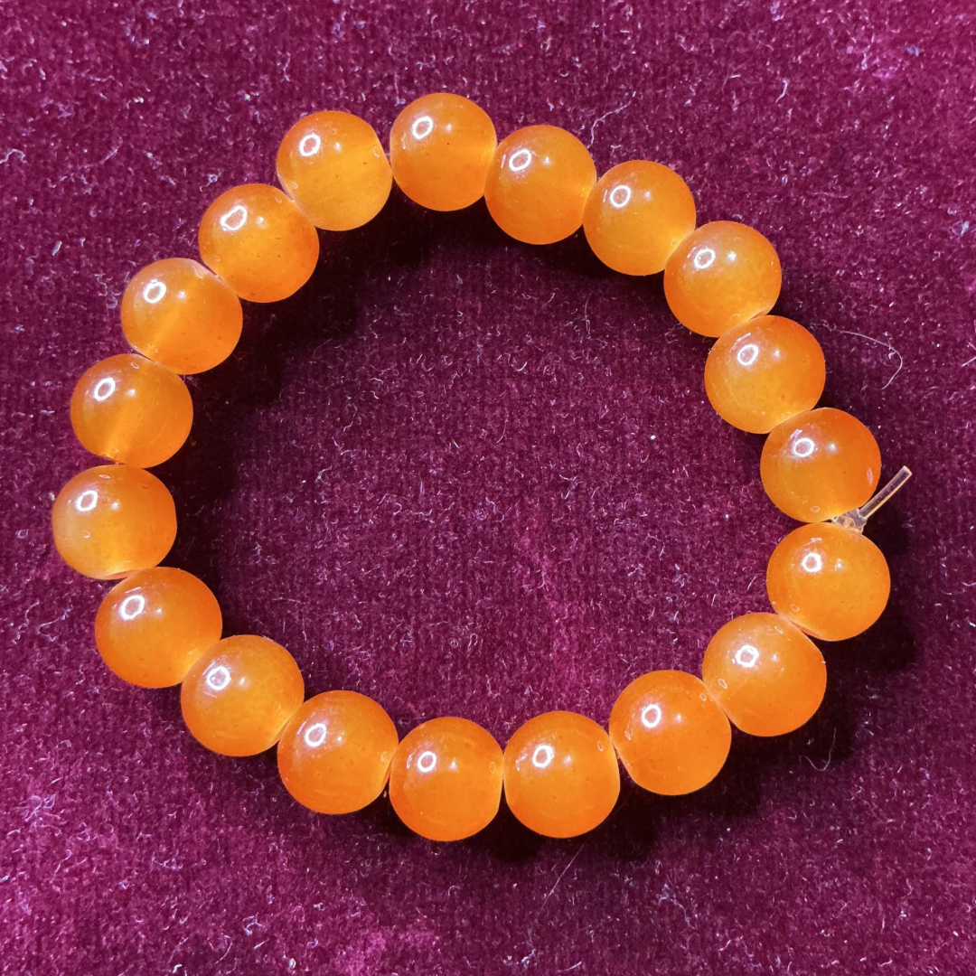 Orange beaded bracelet on a purple textured background