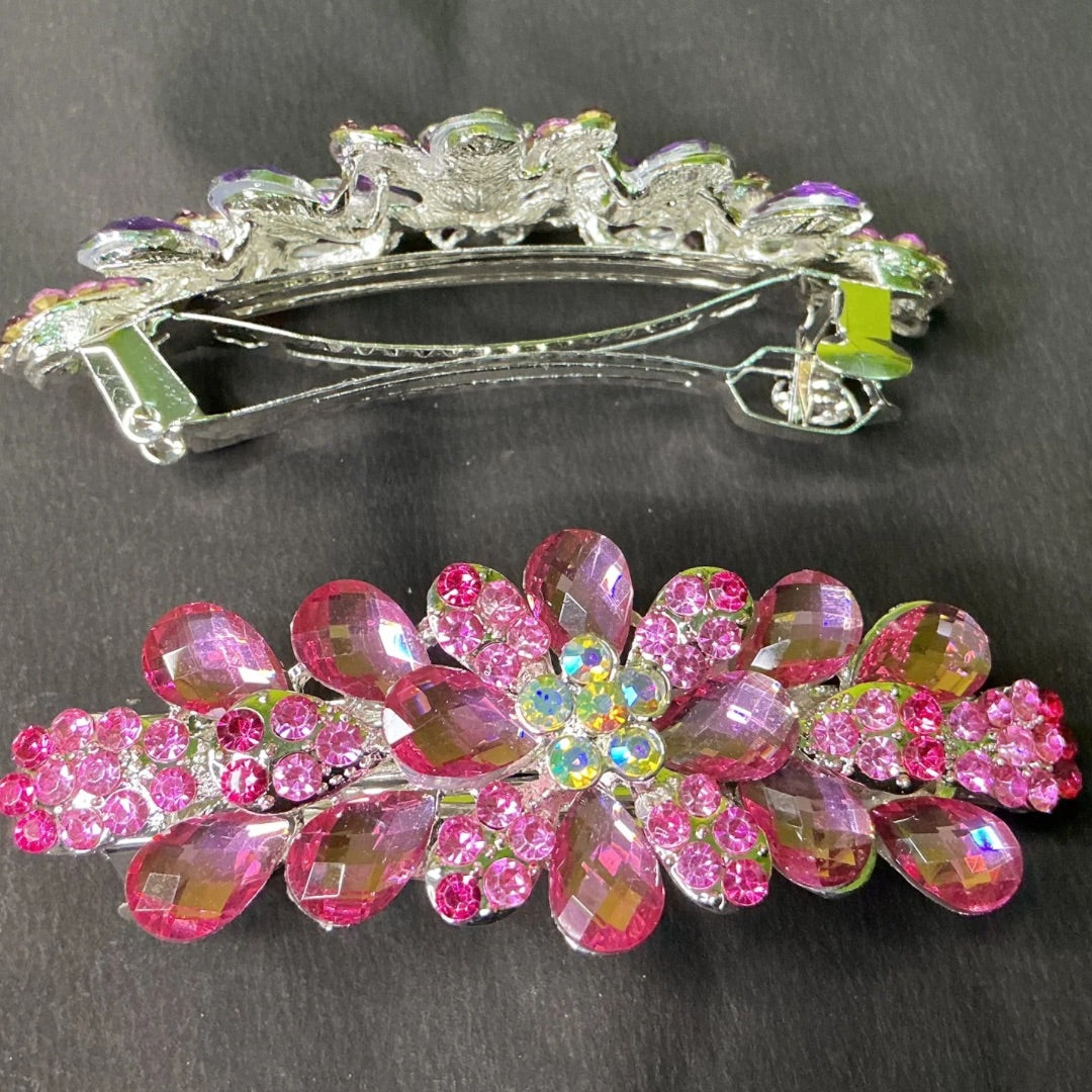 Decorative hair clip with pink floral design and clear crystals on a dark background