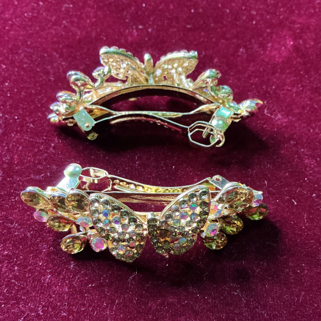 Two decorative butterfly hair clips on a purple background